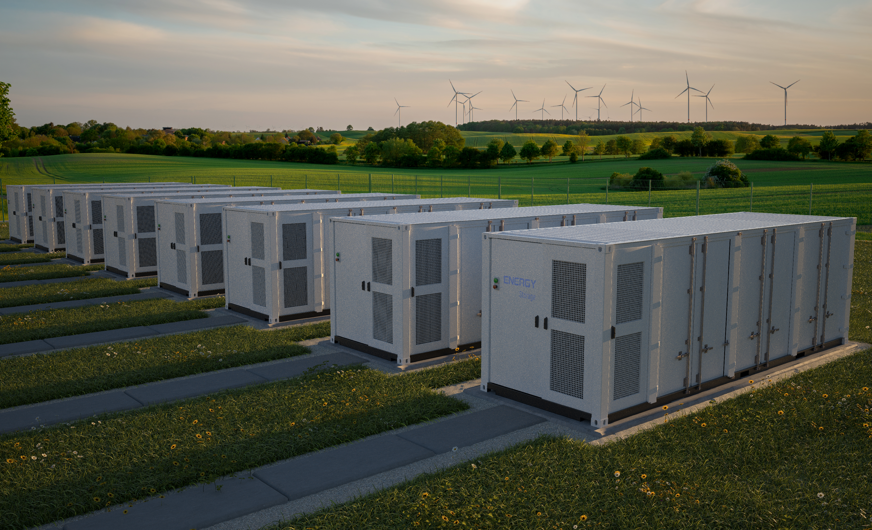Großer Batteriespeicher aus mehreren weißen Container-Modulen, aufgestellt auf einer grünen Wiese, umgeben von natürlicher Landschaft unter freiem Himmel.