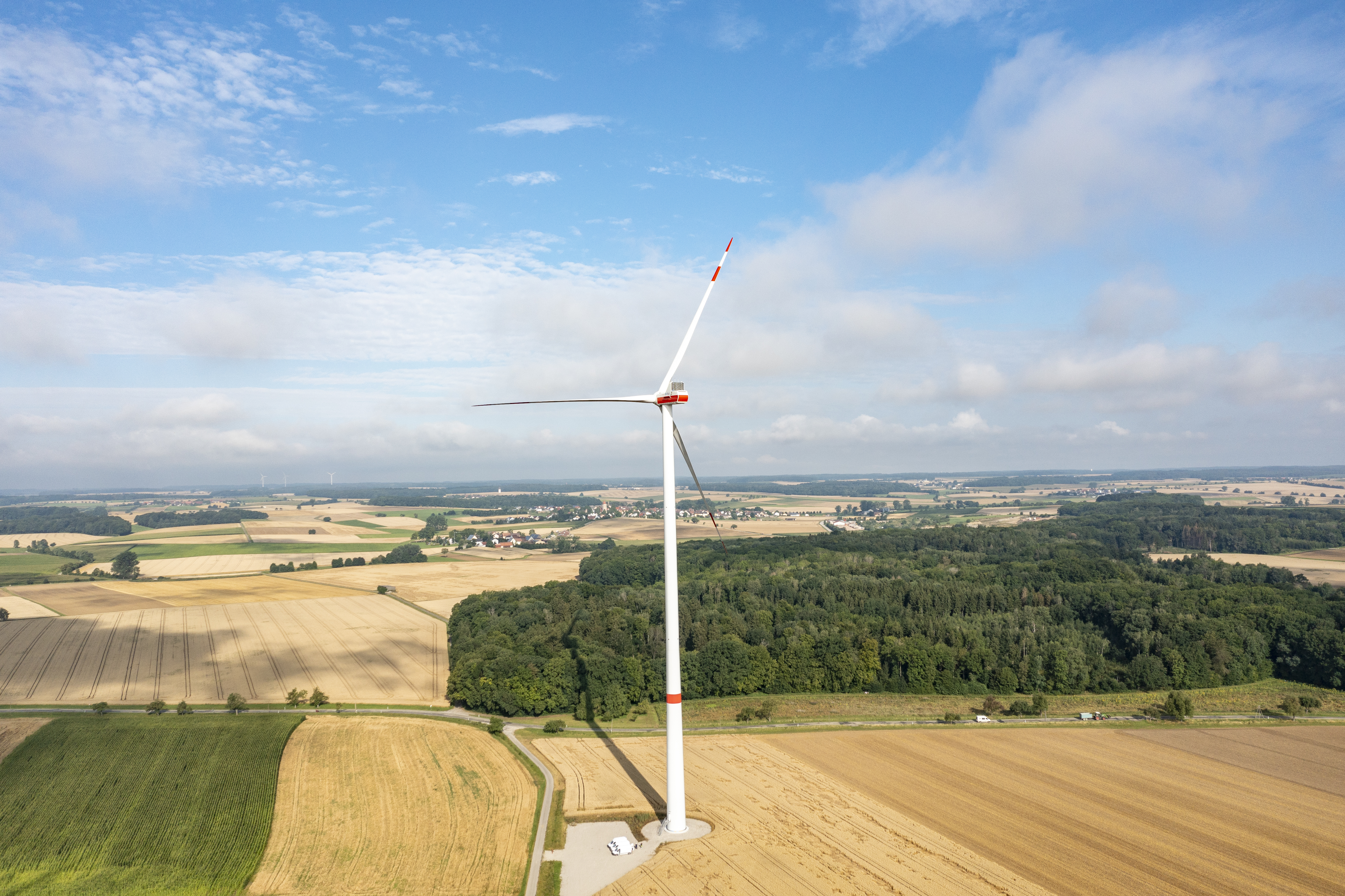 Ein Windrade auf einem Feld bei strahlendem Sonnenschein.