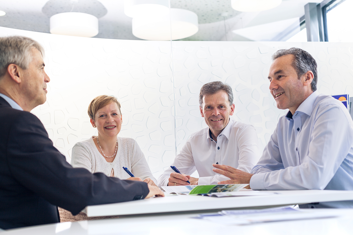 Drei Männer und eine Frau sitzen bei einem Meeting 