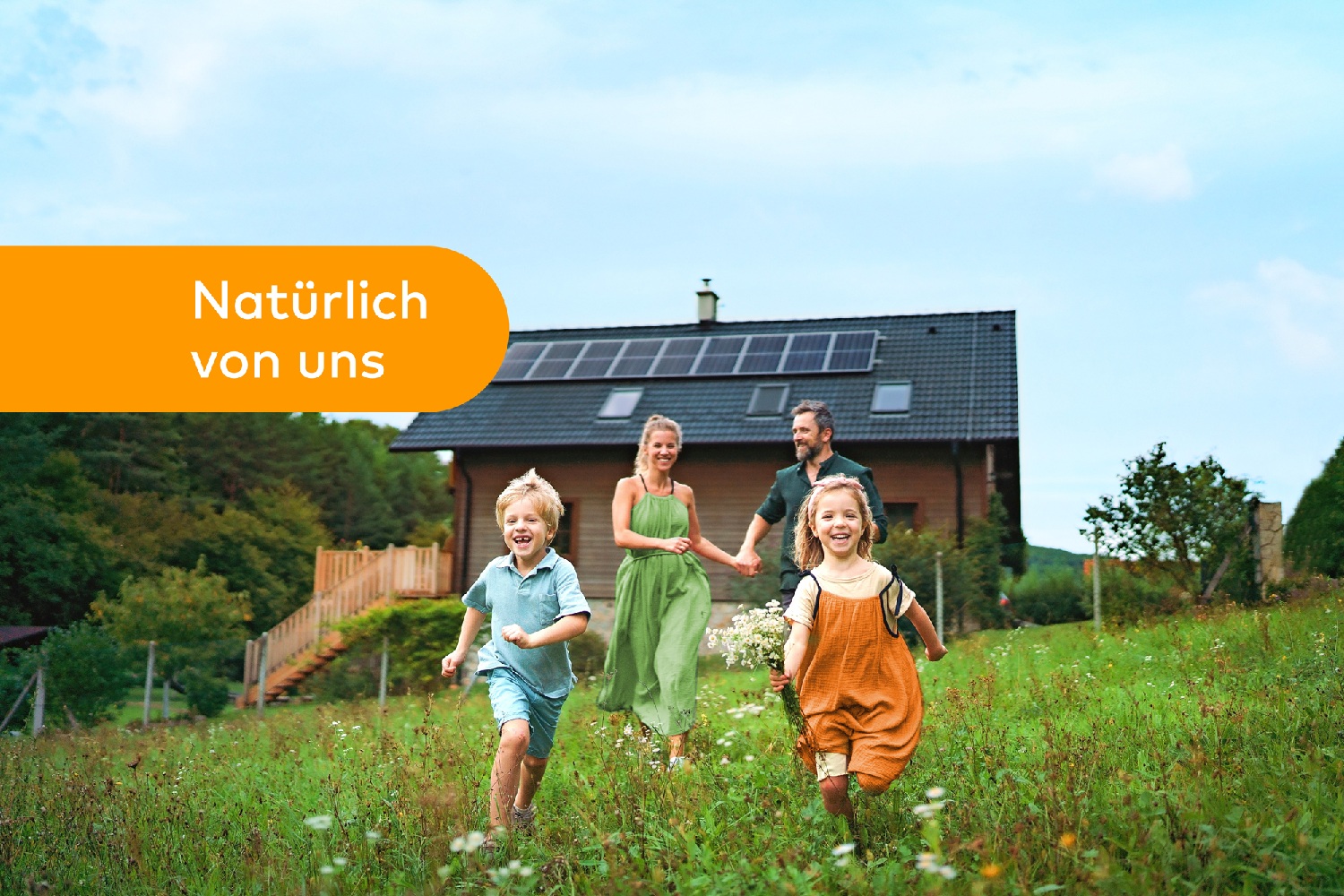 Eine Familie läuft auf einer Wiese an ihrem Haus