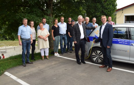 Einweihung Ladesäule Jagstzell Vor einem Auto stehen Personen.