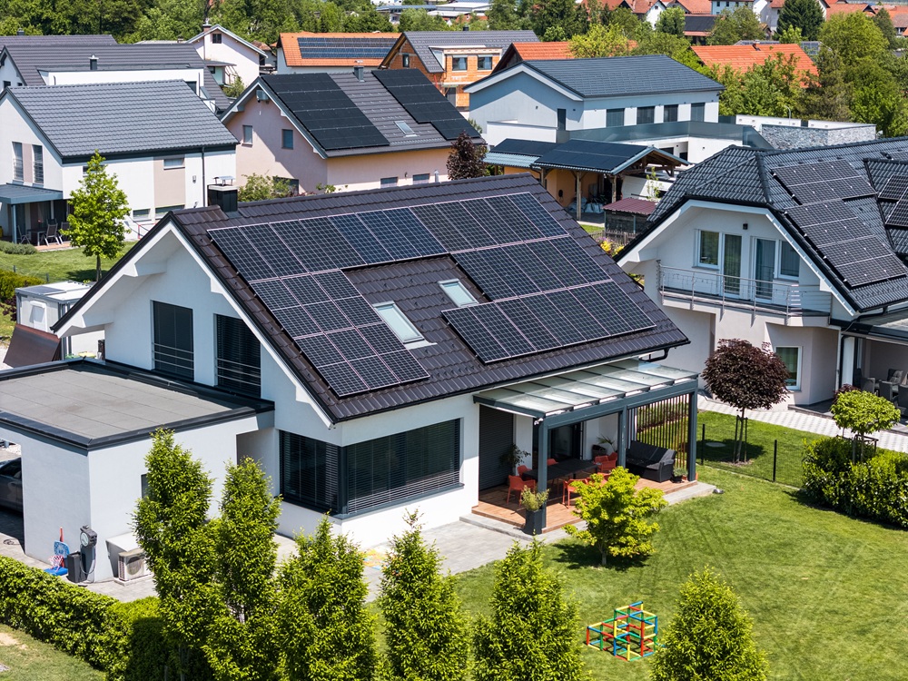 Eine Wohnsiedlung mit Einfamilienhäusern. Es gibt dort Häuser mit PV-Anlage auf dem Dach und Häuser ohne PV-Anlage in der Nachbarschaft.