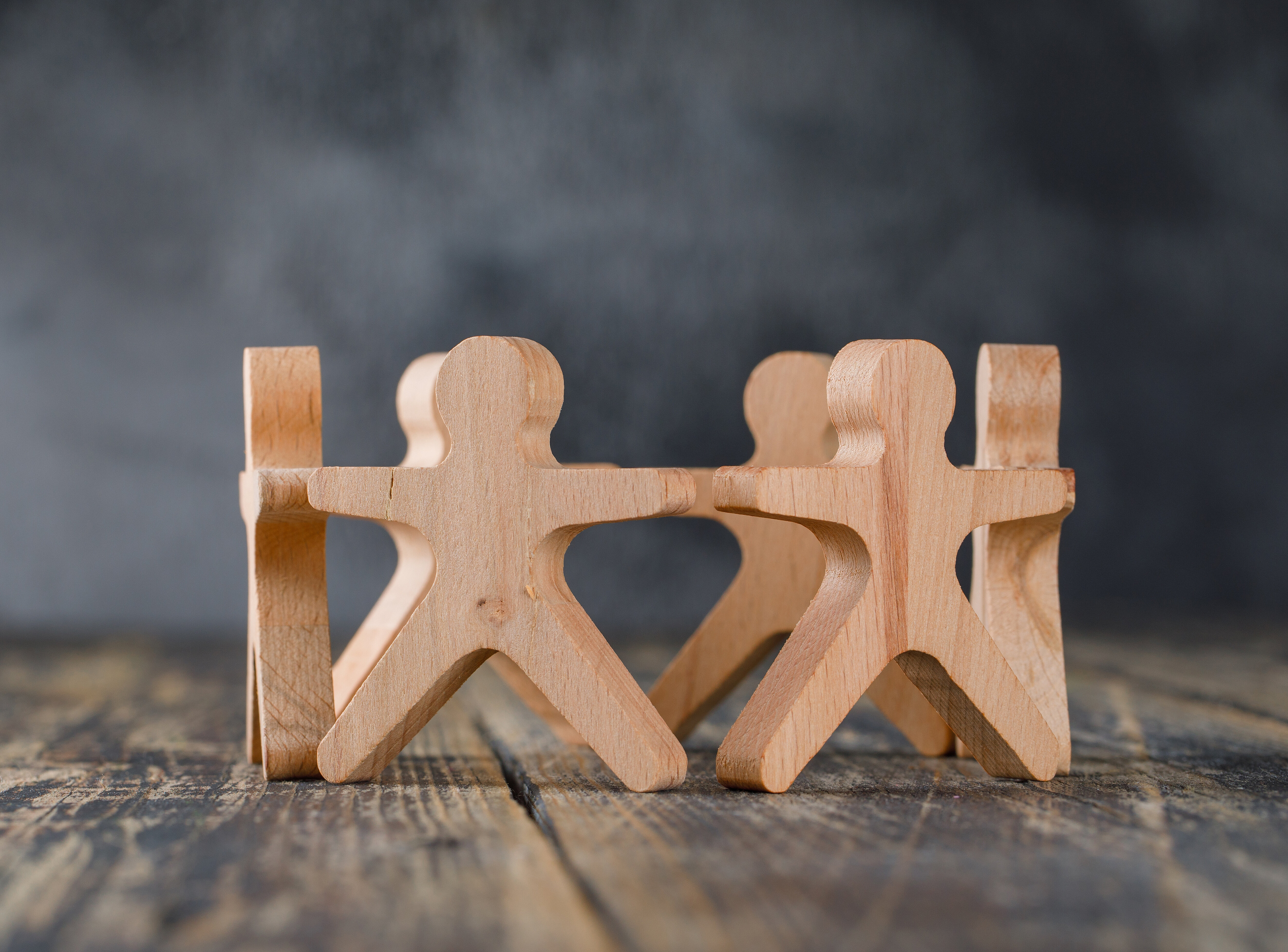 Sechs Holzmännnchen stehen zusammen im Kreis.