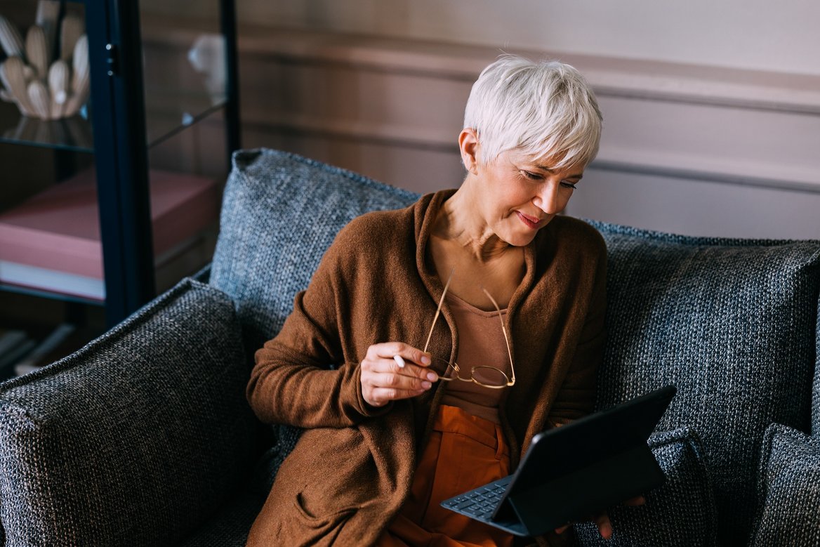 Eine Kundin auf dem Sofa liest an einem Tablet