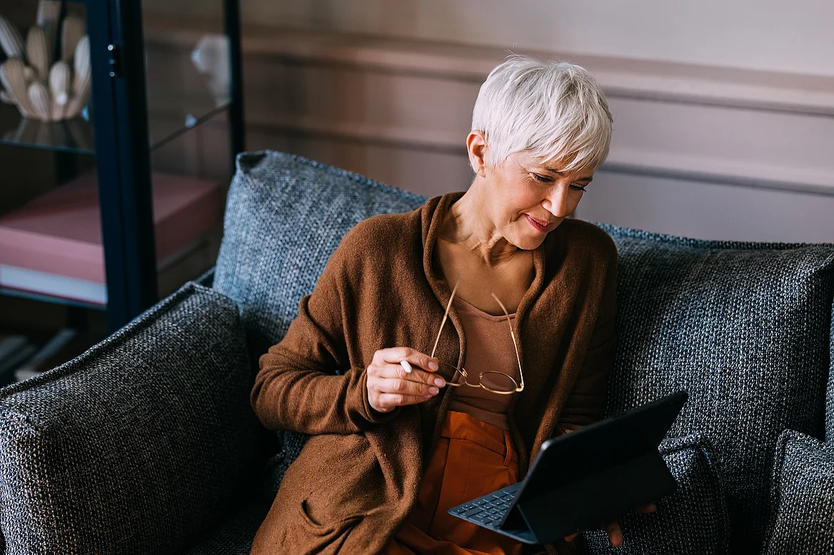 Eine Kundin auf dem Sofa liest an einem Tablet