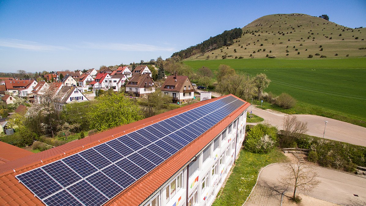 Schuldach mit PV-Anlage, im Hintergrund der Ipf 
