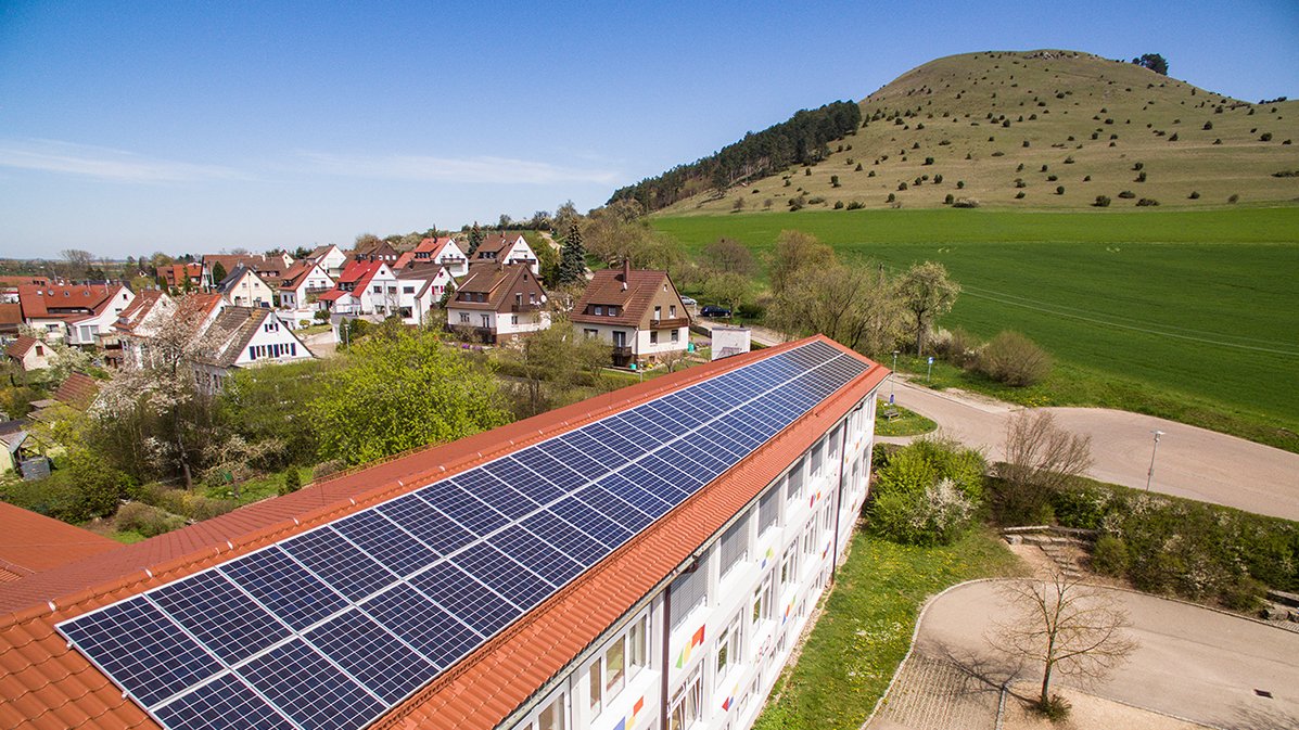 Schuldach mit PV-Anlage, im Hintergrund der Ipf 