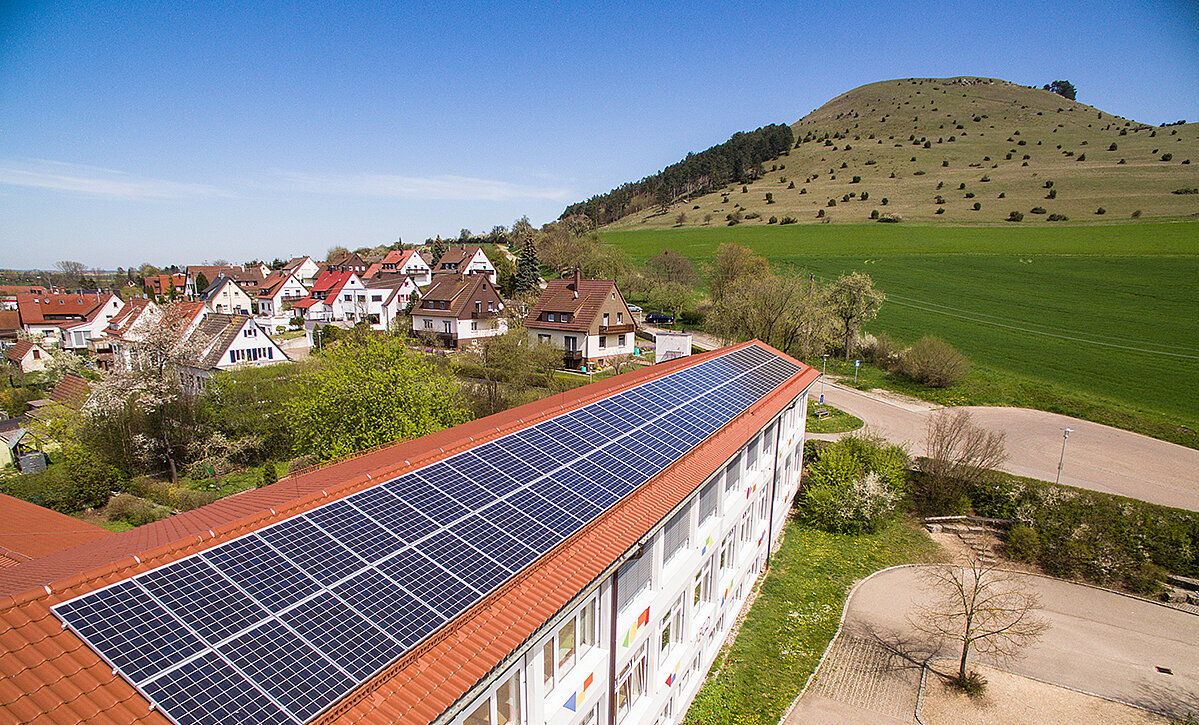 Schuldach mit PV-Anlage, im Hintergrund der Ipf 