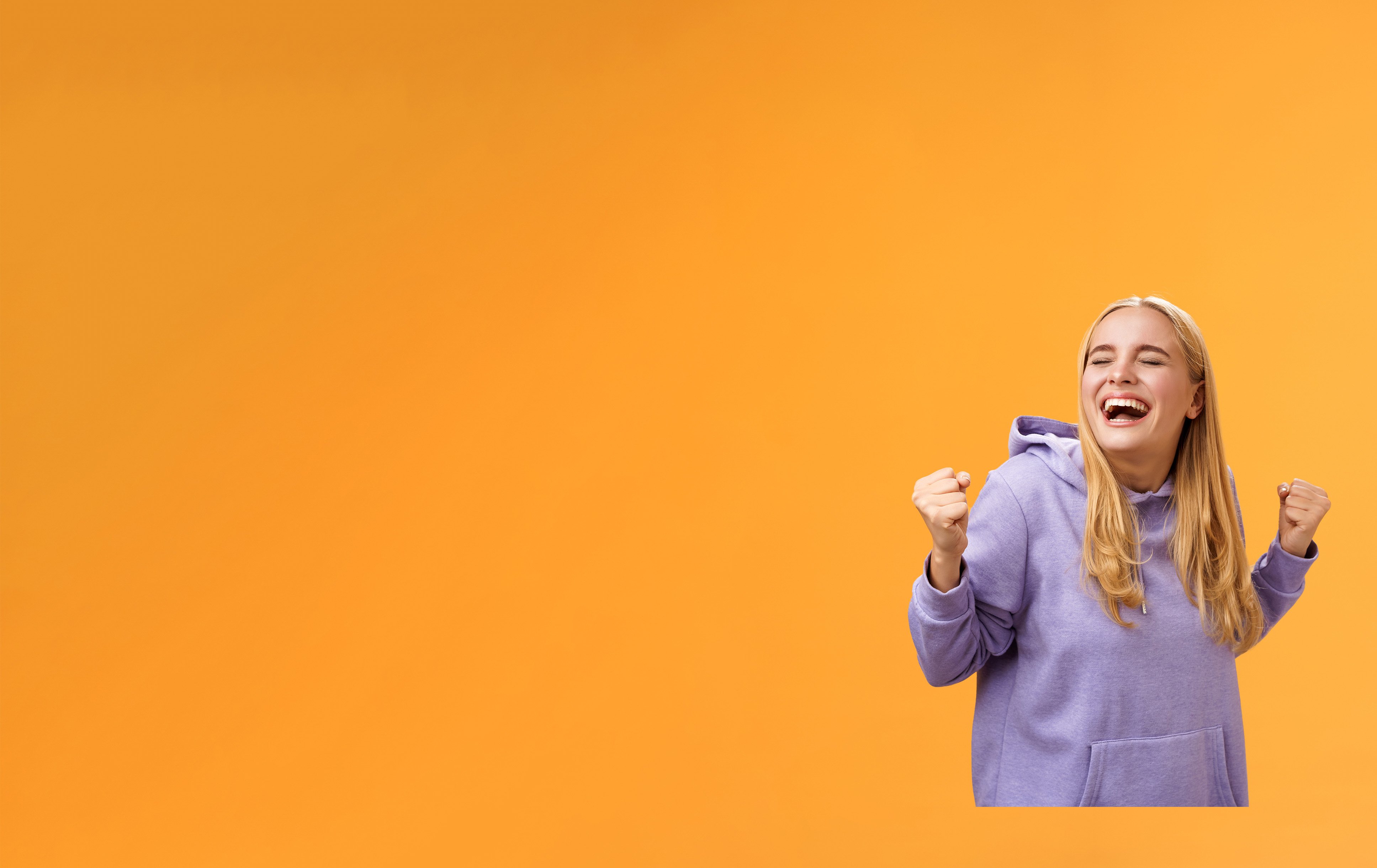 Eine Kundin freut sich sehr über den Gewinn des Treuegewinnspiels der EnBW ODR AG. Sie trägt einen lila Pullover vor orangenem Hintergrund.
