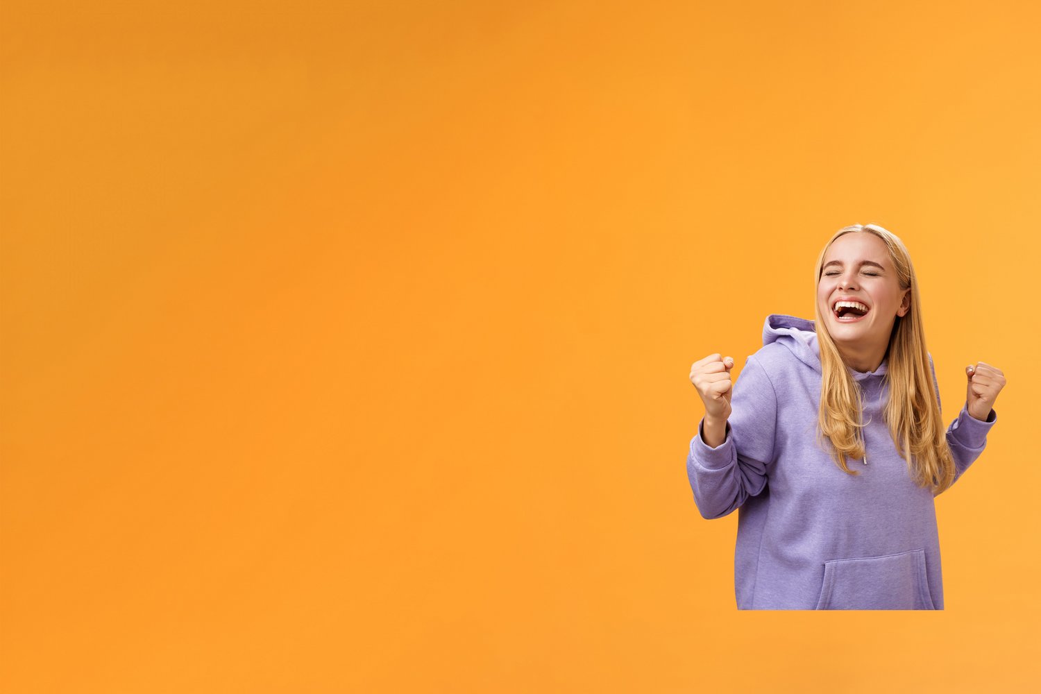 Eine Kundin freut sich sehr über den Gewinn des Treuegewinnspiels der EnBW ODR AG. Sie trägt einen lila Pullover vor orangenem Hintergrund.