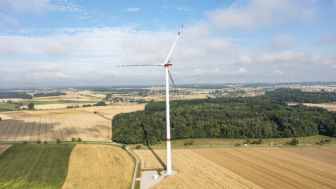 Ein Windrade auf einem Feld bei strahlendem Sonnenschein.