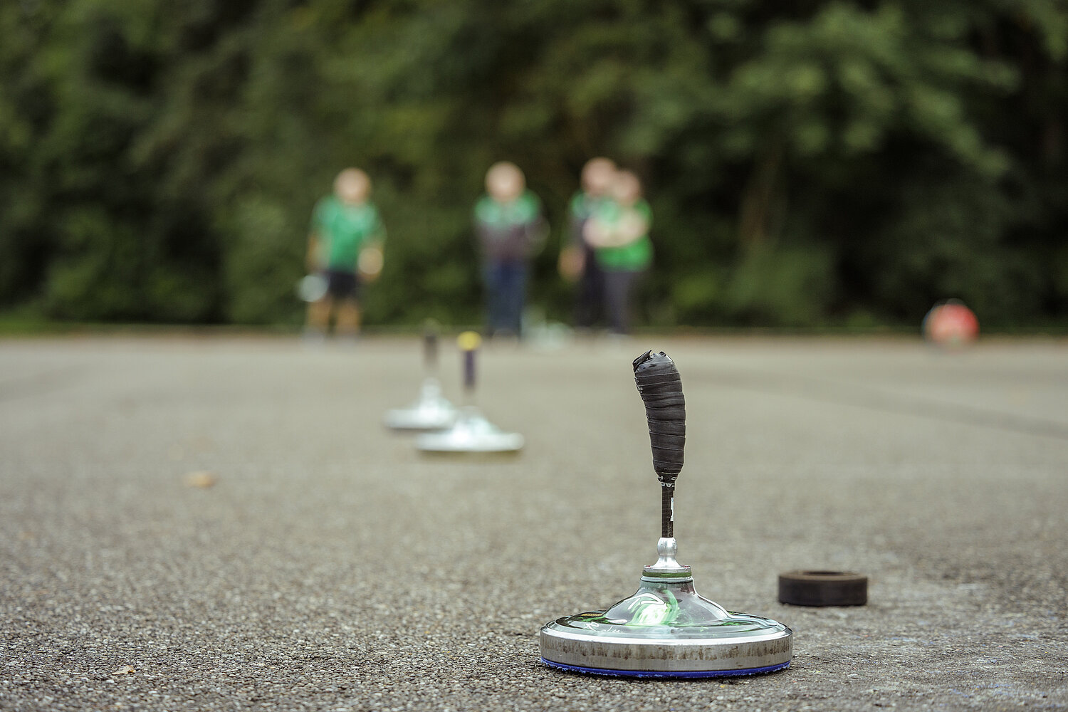 Ein paar Menschen mit Eisstöcken auf einer Asphaltfläche