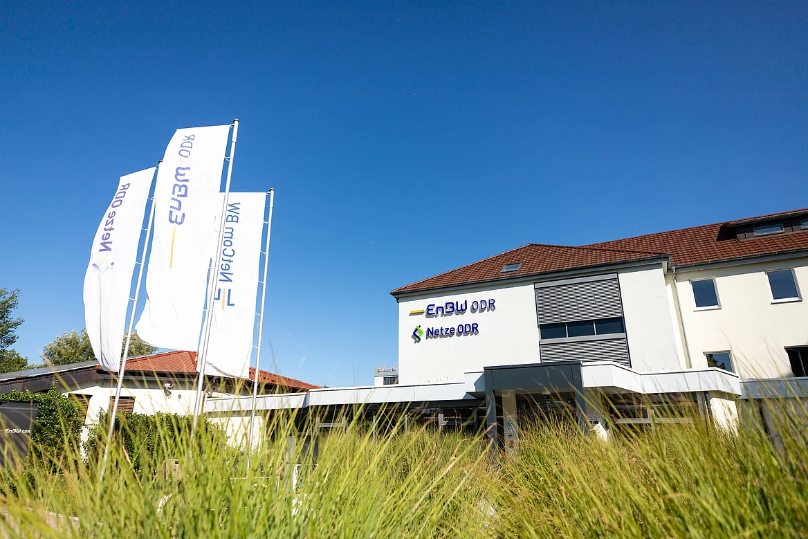 Haupteingang der EnBW ODR AG in Ellwangen bei strahlendem Sonnenschein. An der Fassade sind die Logos der EnBW ODR AG und der Netztochtergesellschaft Netze ODR GmbH zu sehen.