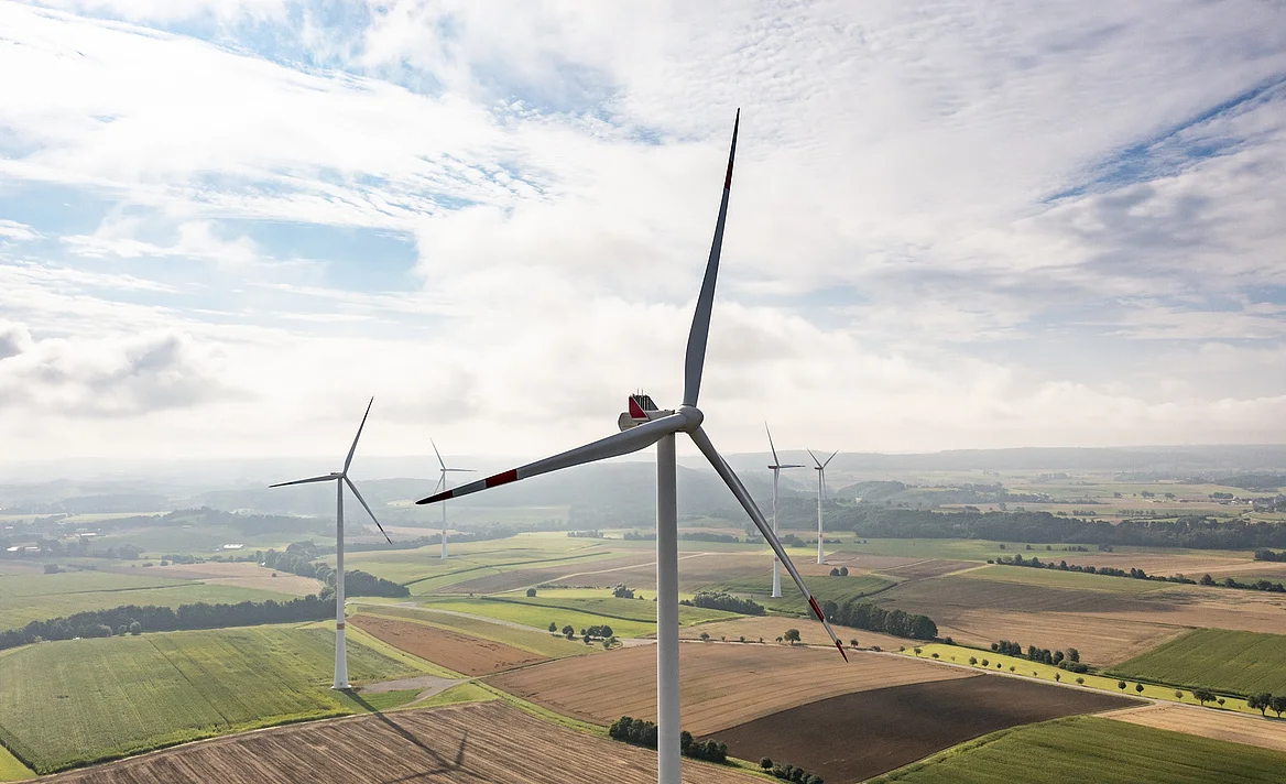 Fünf Windräder bei bewölktem Himmel.