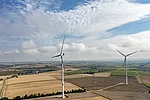 Zwei Windräder auf einem Feld bei Sonnenschein.