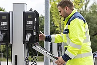 Ein Mitarbeiter wartet eine Ladesäule auf einem Kundenparkplatz.