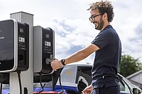 Ein Mitarbeiter greift eine Ladevorrichtung für ein Elektrofahrzeug