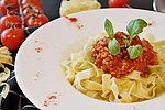 Teller mit Bandnudeln, Tomatensauce und Basilikum