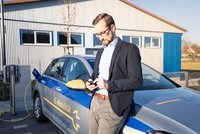 E-Auto_warten_vollgeladen Ein Mann steht vor seinem E-Auto und wartet auf den fertigen Ladevorgang