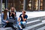 Hochschule Schüler sitzen vor dem Gebäude und bearbeiten etw. am Laptop