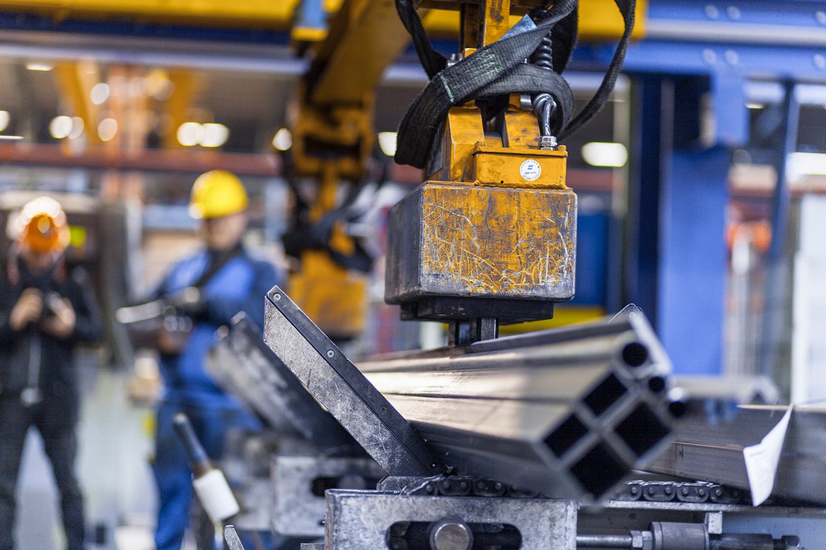 Maschinenhalle Zwei Männer überwachen eine Maschine beim Arbeiten mit Metall